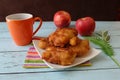 Apple fritter, pieces ofÃÂ appleÃÂ deep-fried in batterÃÂ served with a cup of black coffee and fresh apples on the wooden table.